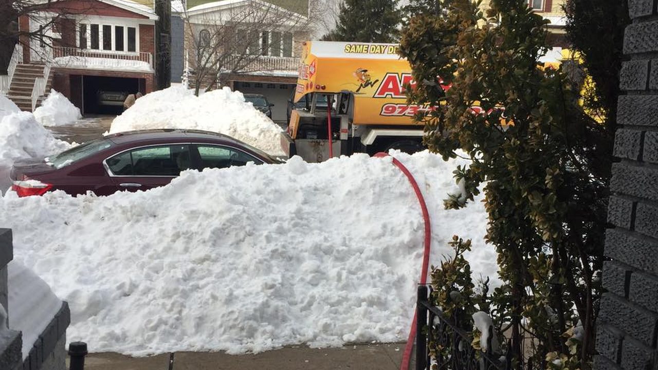 An Ariba Oil delivery hose running over a deep snowbank to a house fill pipe.