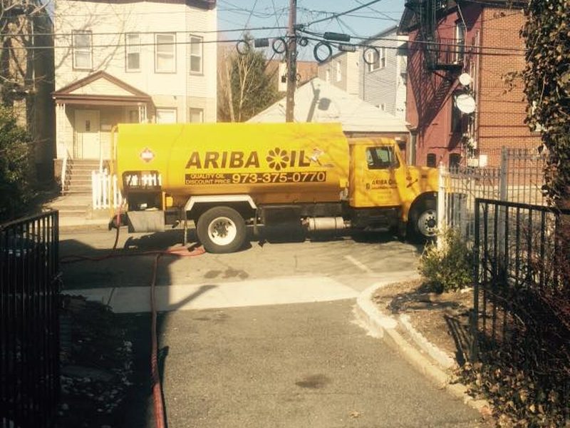 A yellow Ariba Oil truck making a residential heating oil delivery.